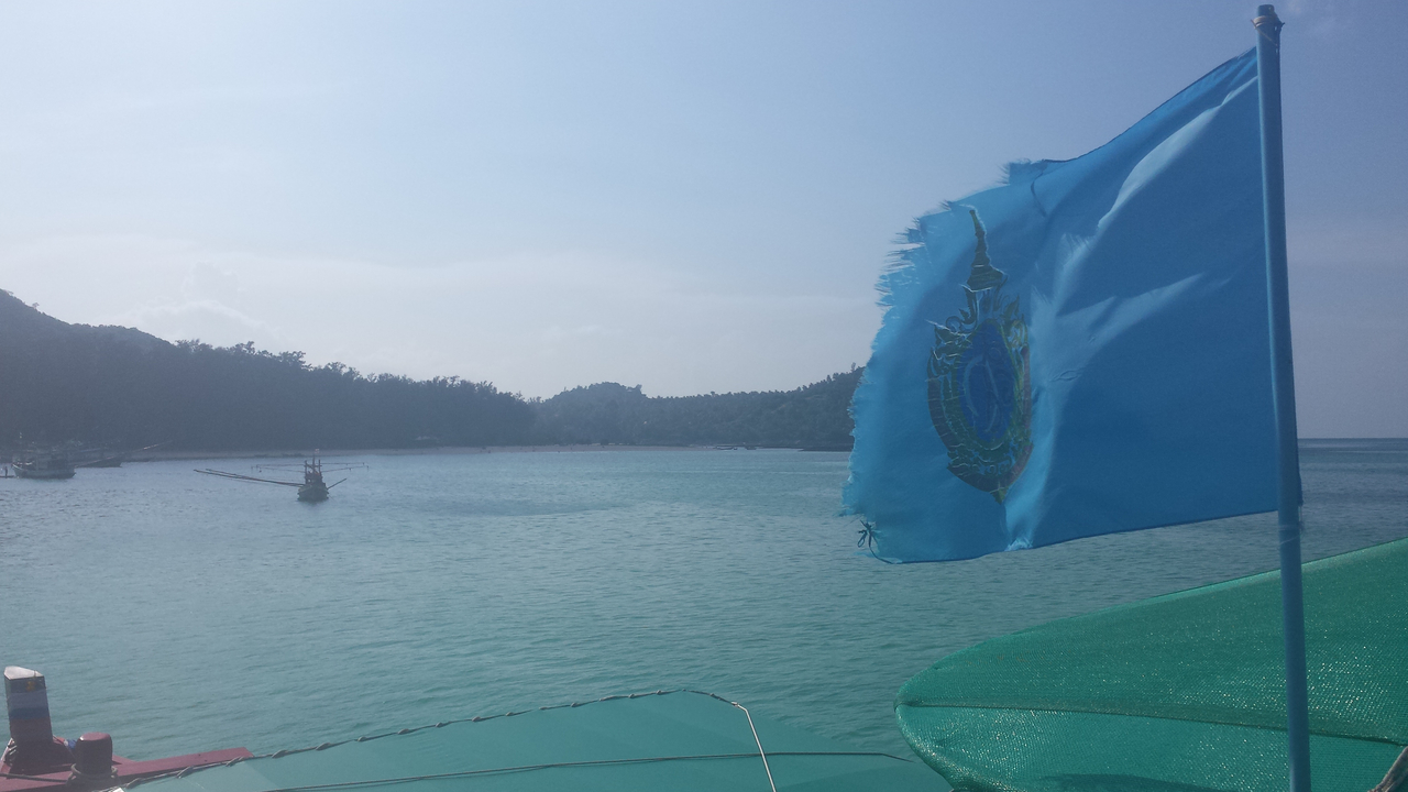 Flag fluttering on a clear day over a body of water.