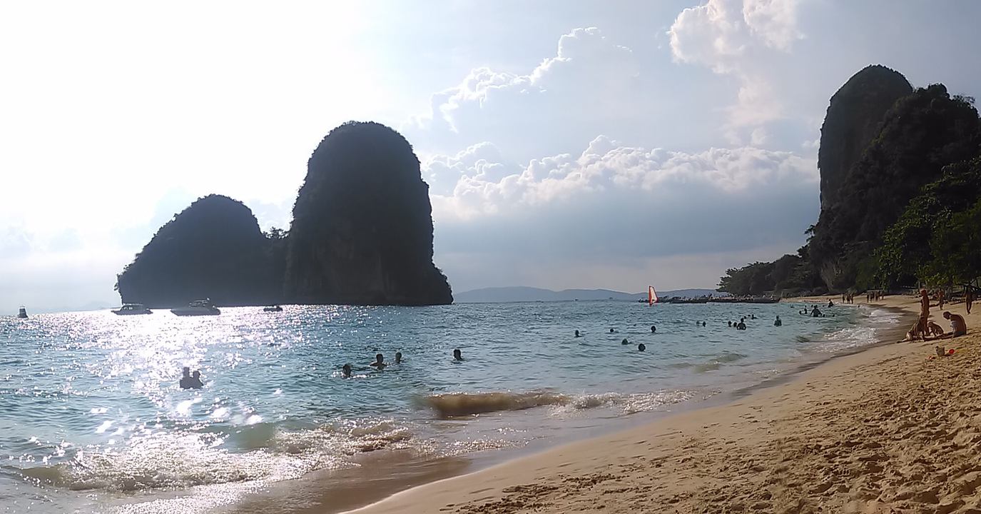 Picturesque beach with swimmers and limestone cliffs.