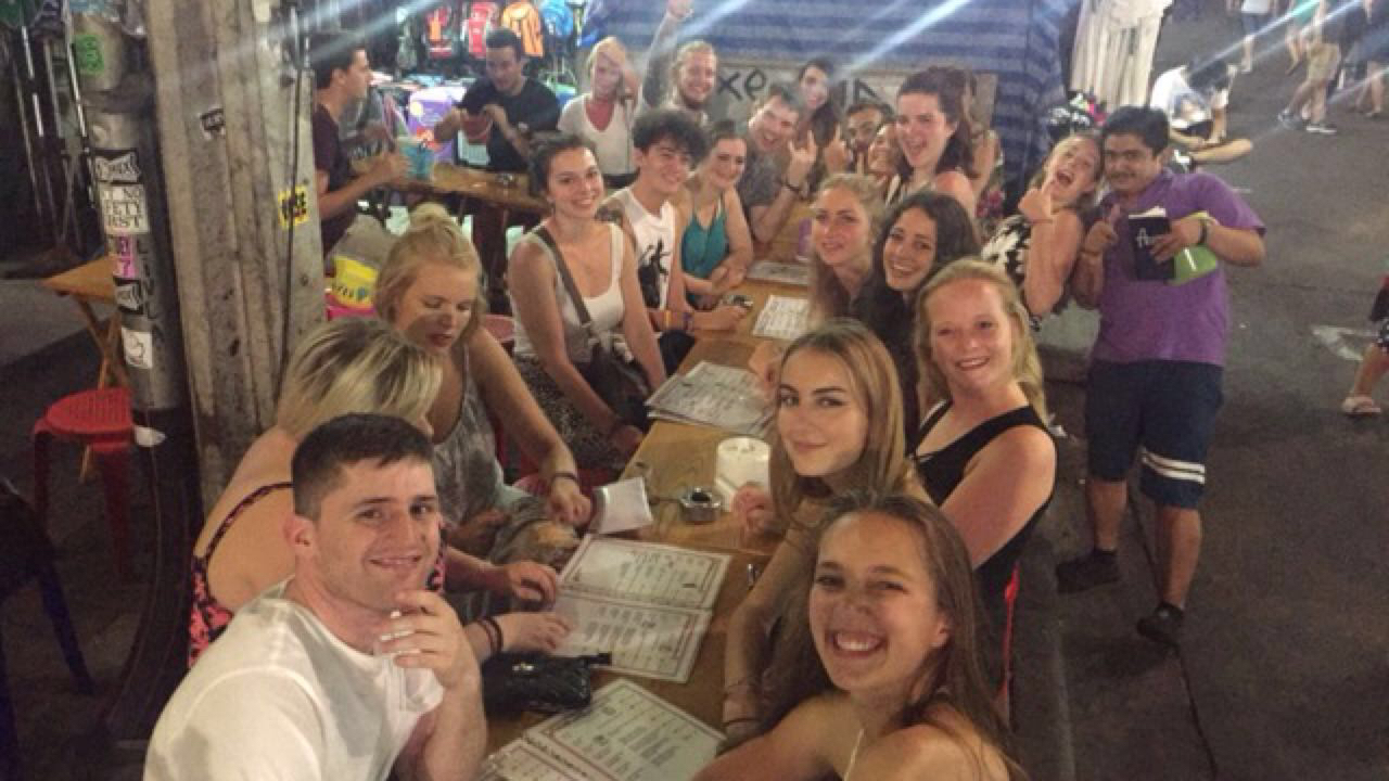 Large group dining outdoors at night.