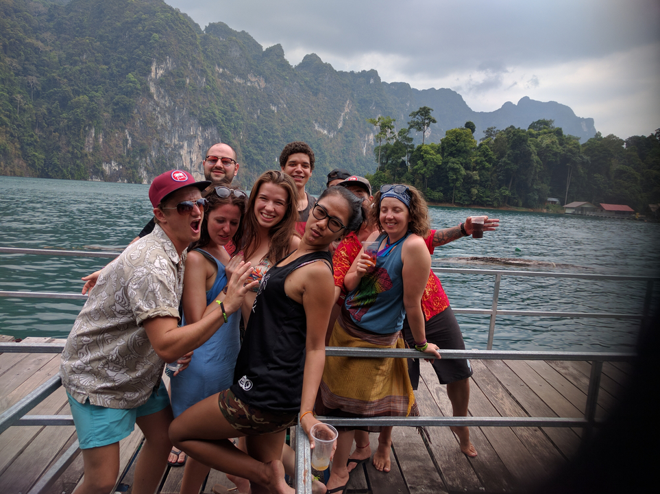 Group of friends posing playfully on a dock by a lake.