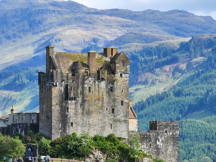 A stone castle with mountains in the background.