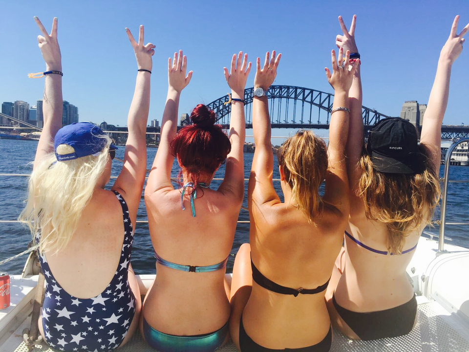 People enjoying a boat ride with Sydney Harbor Bridge in view.