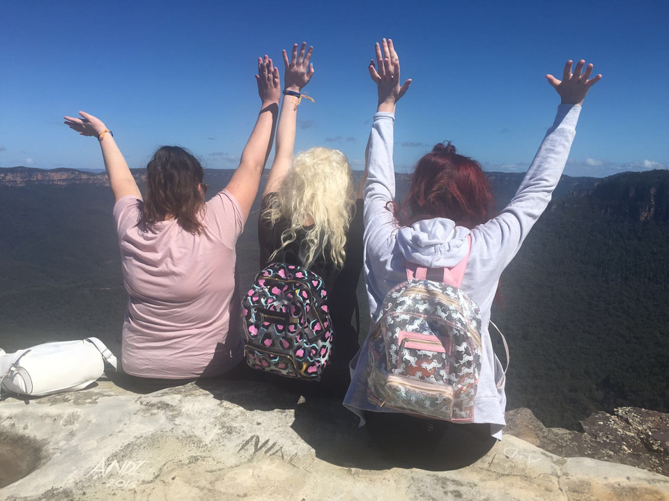 Three women at a scenic location with backpacks.