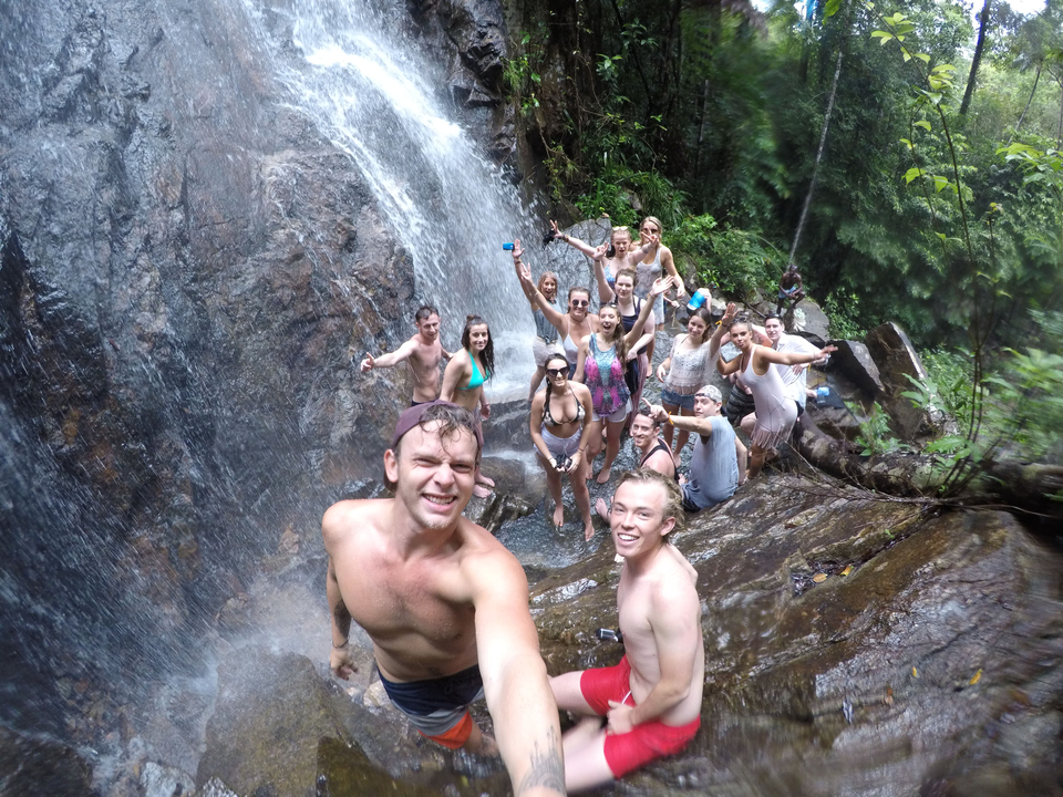 Large group of people posing at a waterfall.