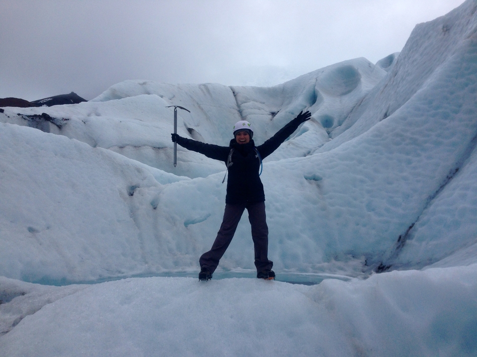 Person posing with an ice axe in a glacial area.