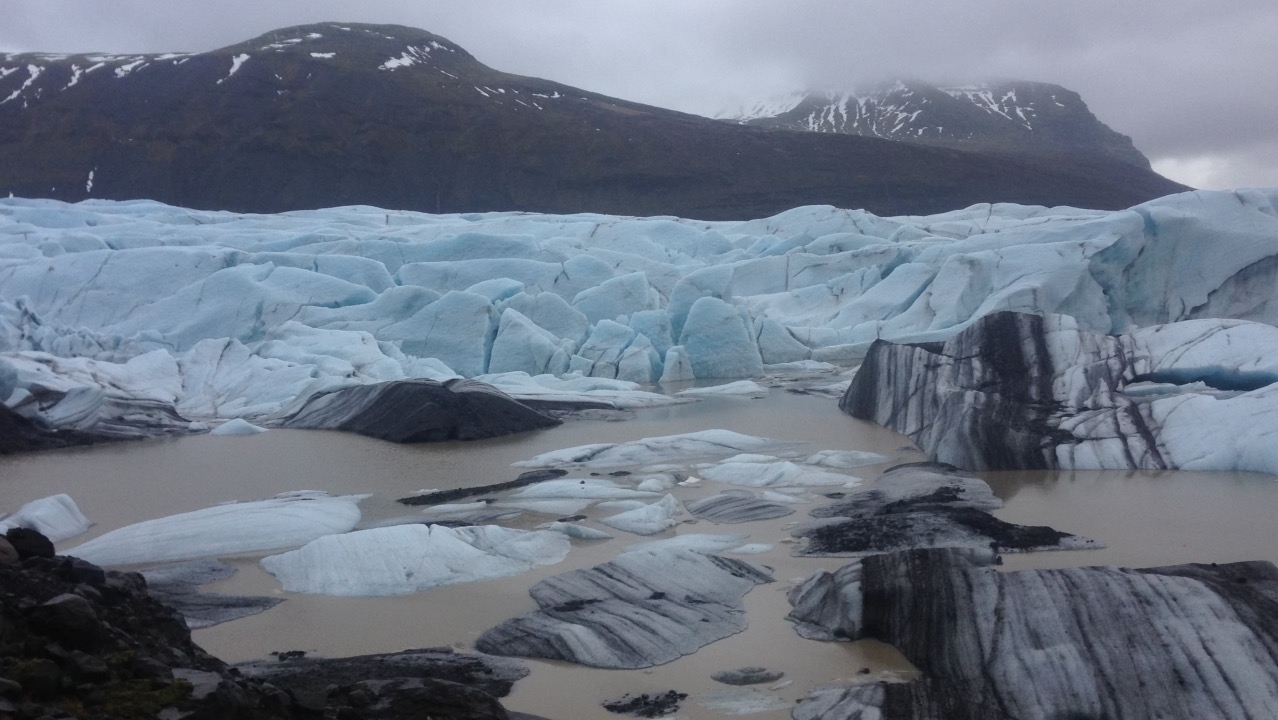 Vast glacier with ice formations and cloudy sky.
