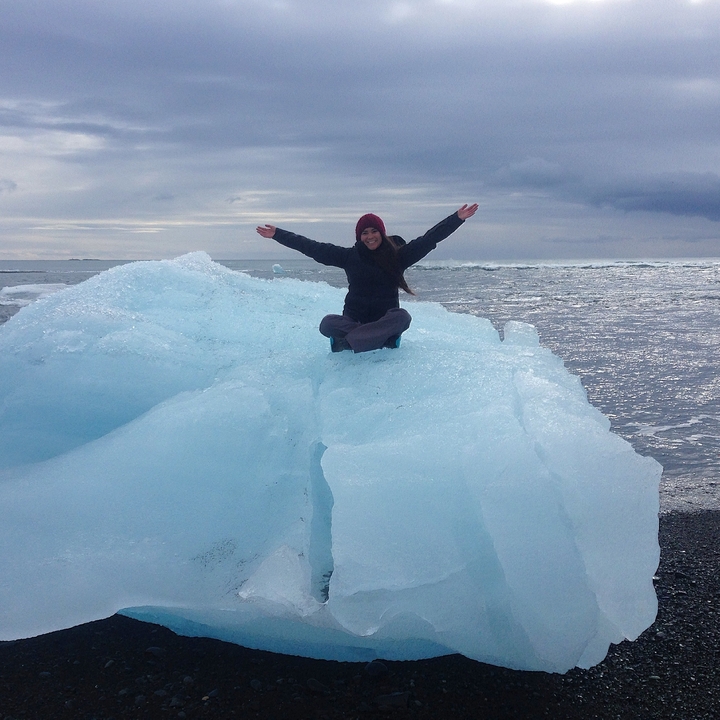 Person sitting on an iceberg in a vast icy landscape.