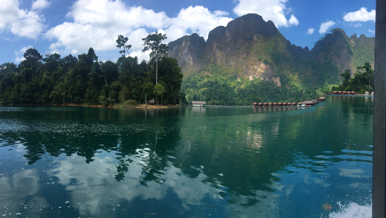 Serene lake surrounded by lush forest and mountains.