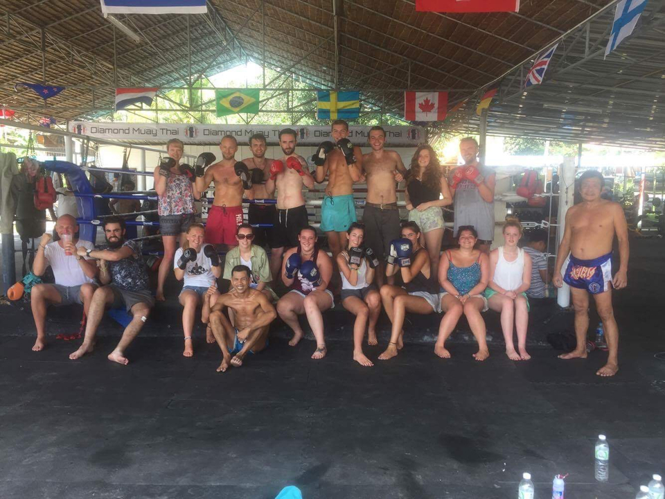 Group of people in a boxing gym posing with gloves.