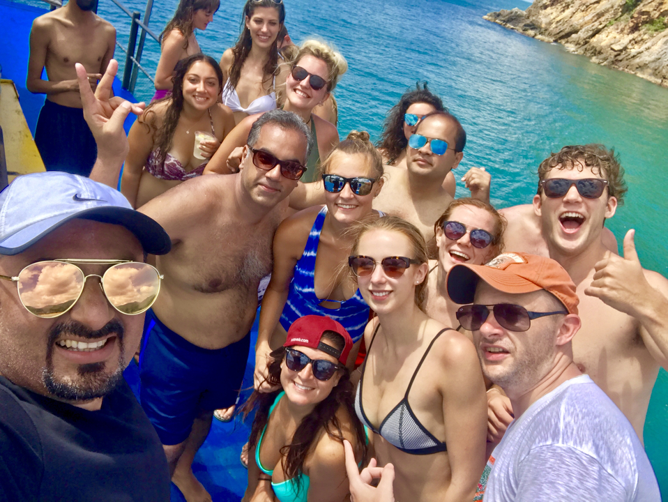 Group selfie with people on a boat in turquoise waters.