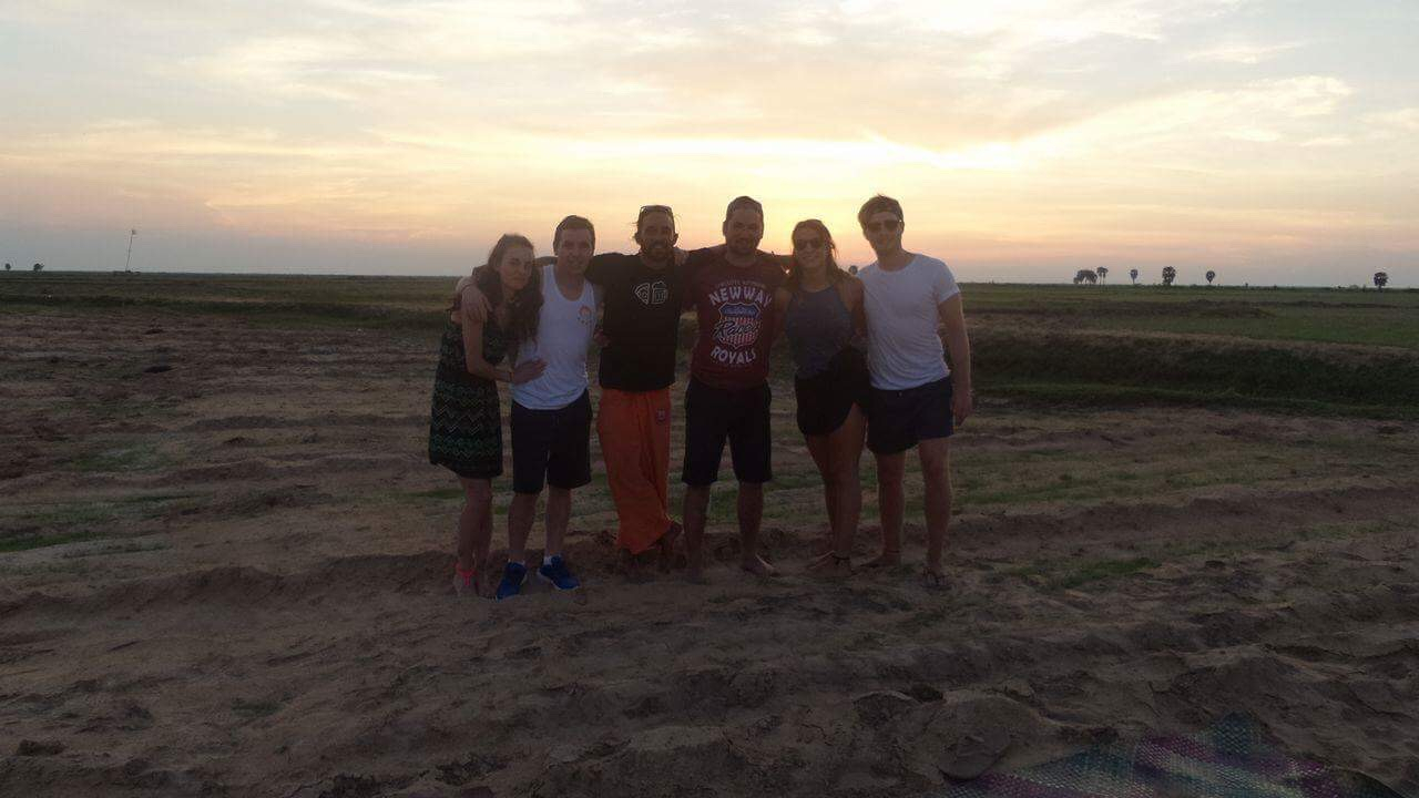Group of people standing together at sunset.