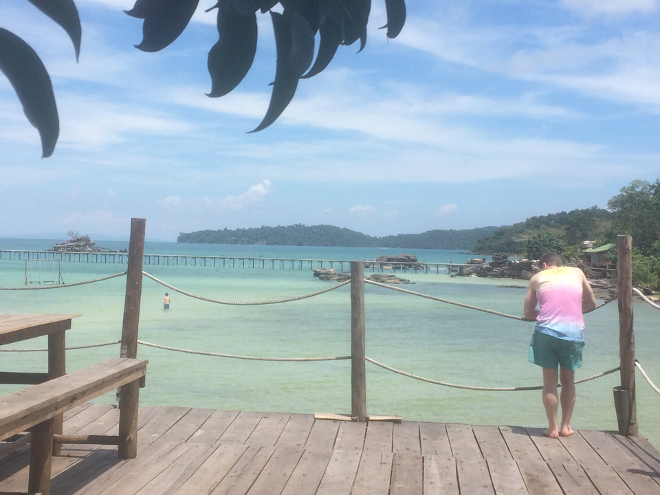 Scenic beach with a long pier and clear waters.