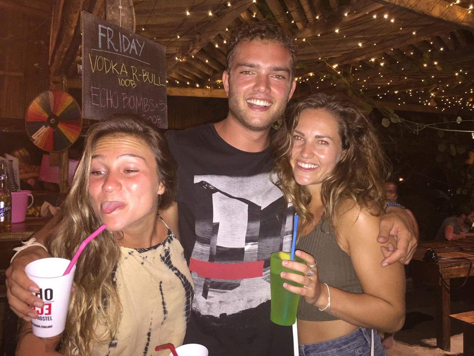 Group of people enjoying a night out with drinks under decorative lights.