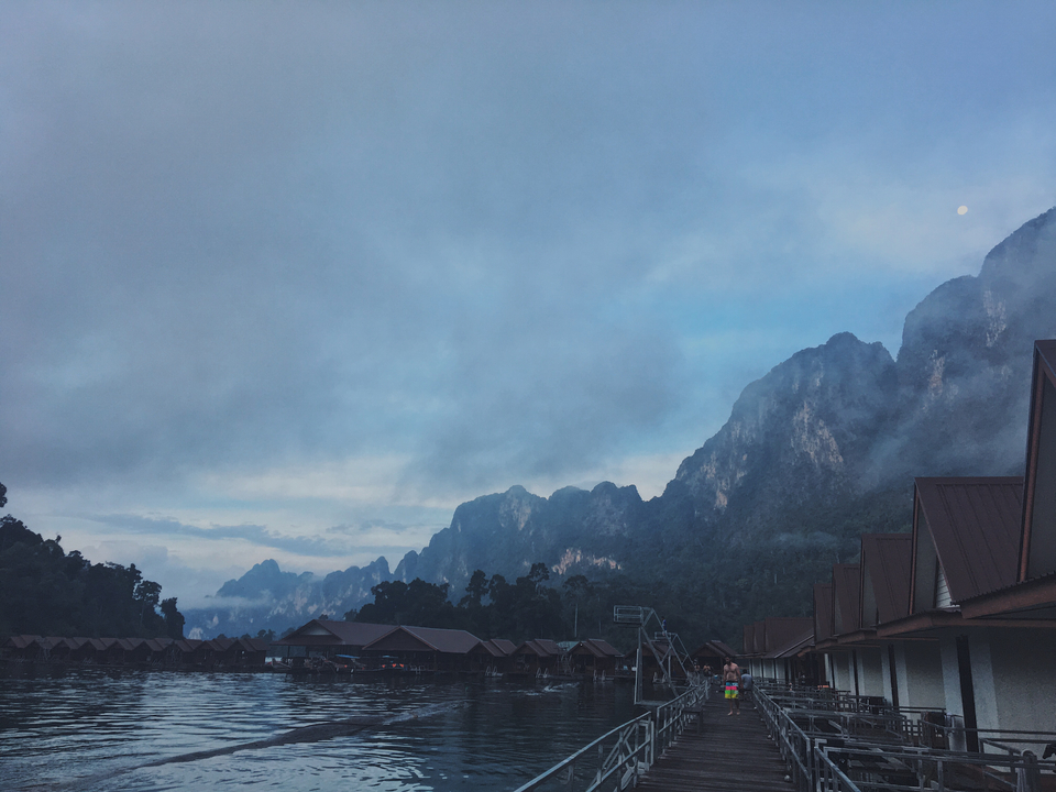 Mountainous landscape with mist over the hills and huts in the foreground.