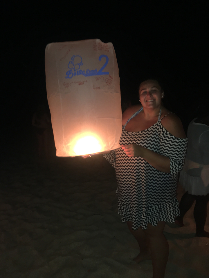 Person holding a lantern on a beach at night.