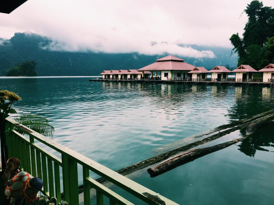 Overwater bungalows on a serene lake surrounded by mountains.