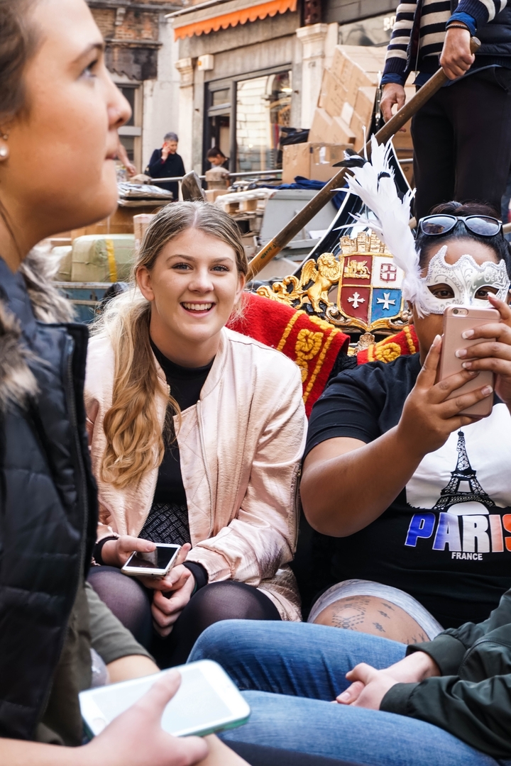 Two people in costumes on a gondola, one taking a selfie.