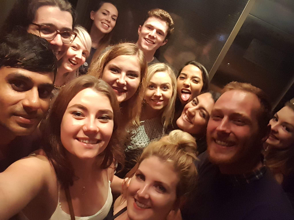 Group selfie in a crowded room.