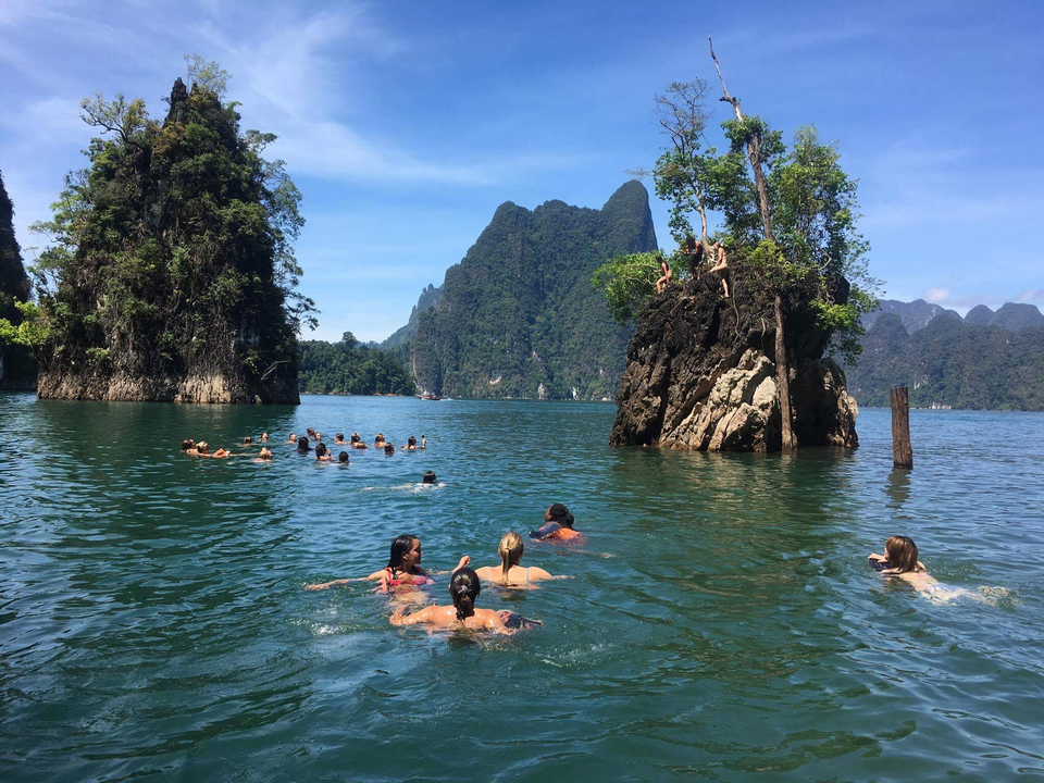 People swimming near limestone cliffs in a turquoise lake.