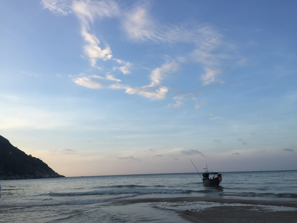 A boat floating on calm waters during sunset.