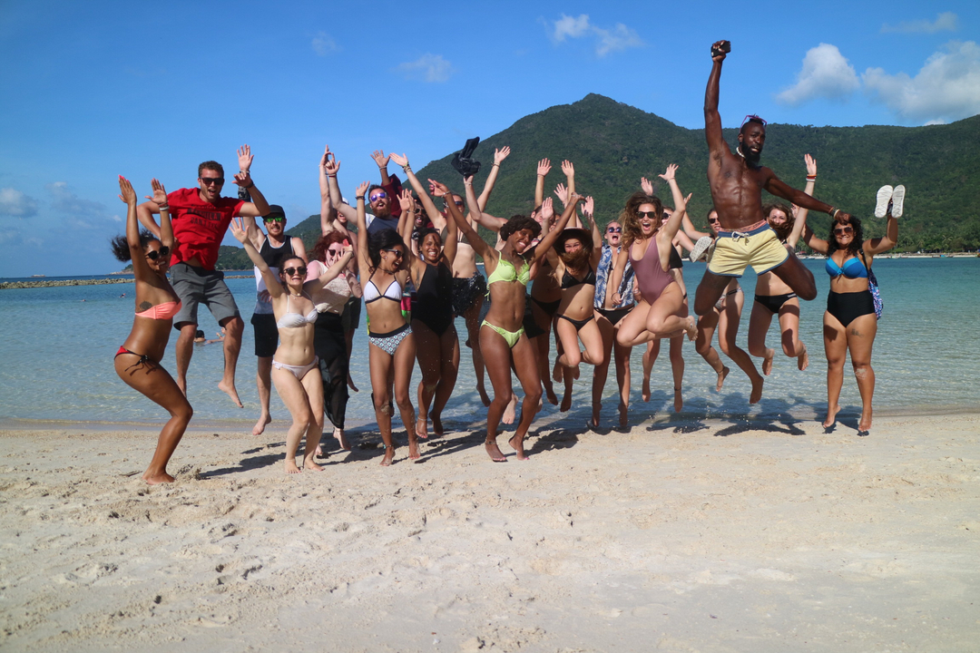 Large group of people jumping happily on the beach.