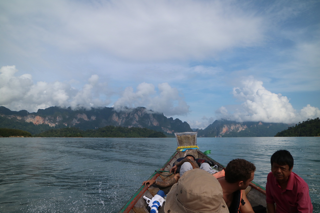 People on a boat in a scenic lake with mountains in the background.