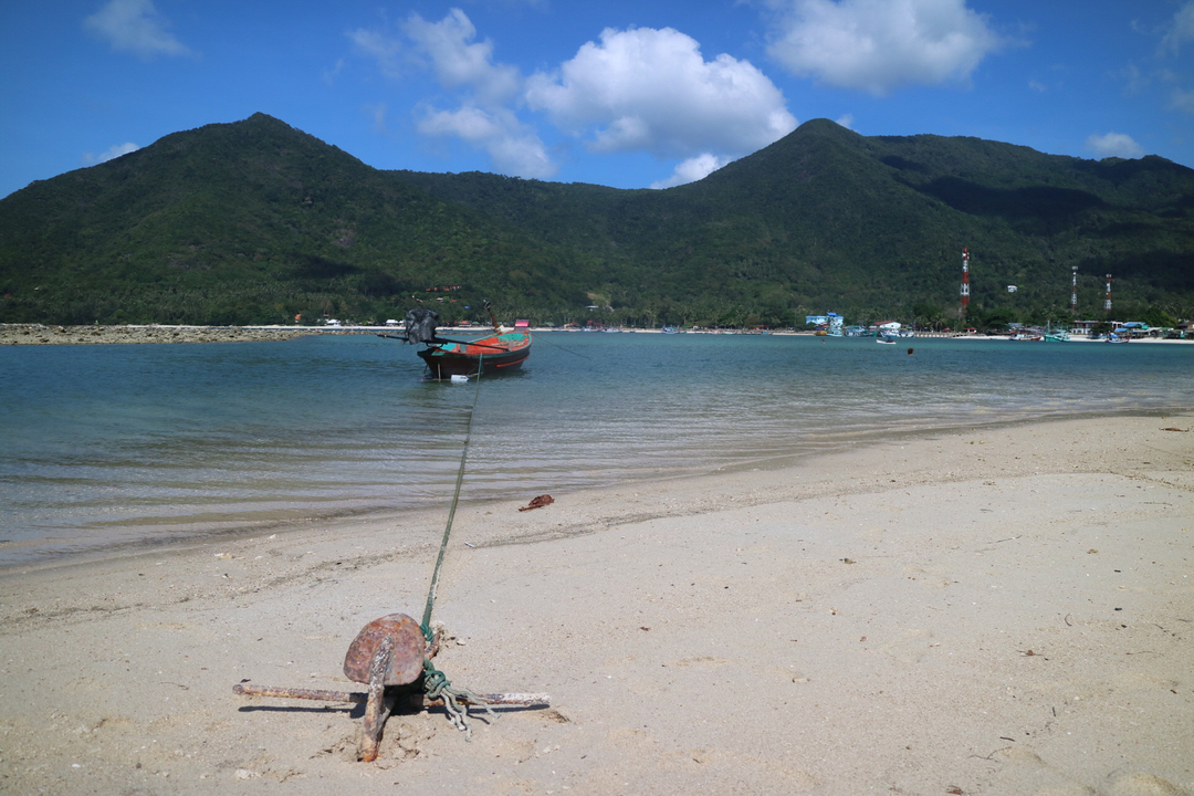 Boat tied to anchor on a tranquil beachside scenery.