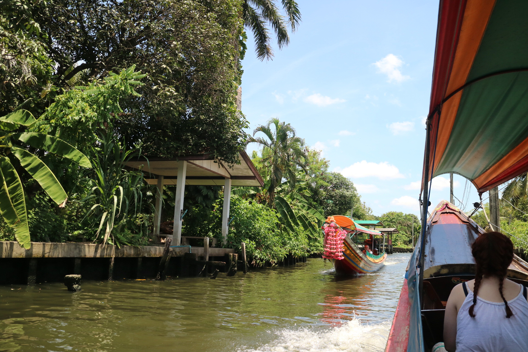 Longtail boat navigating a canal surrounded by lush greenery.