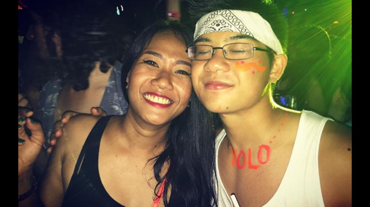 Two people smiling indoors with neon lighting.