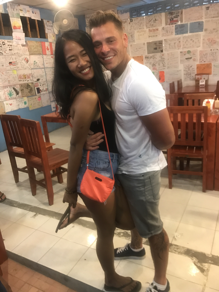 Close-up of two people, one embracing the other in a restaurant.