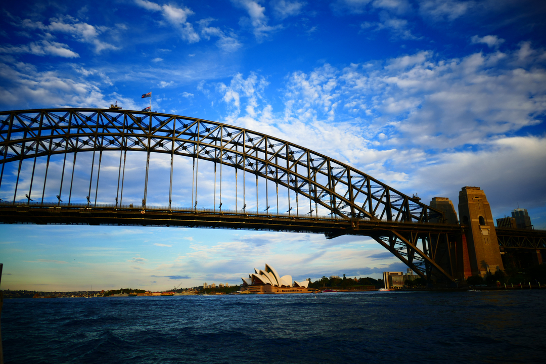 Sydney Harbour Bridge with Operain the background against a blue sky.