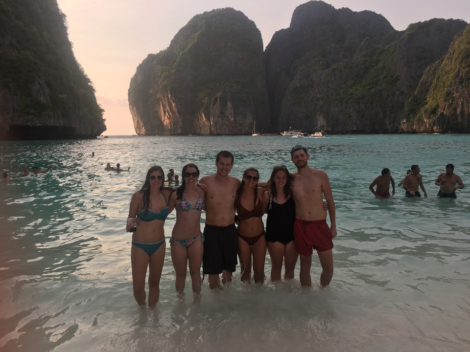 People posing on a beach with stunning cliffs in the background.