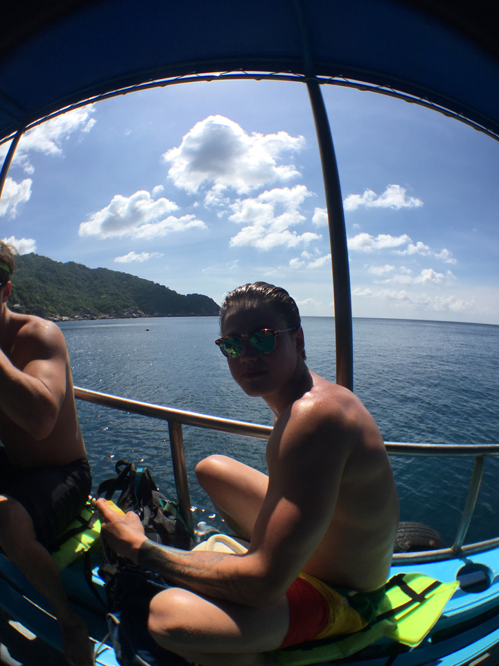 Man sitting on a boat looking at the ocean with hills nearby.