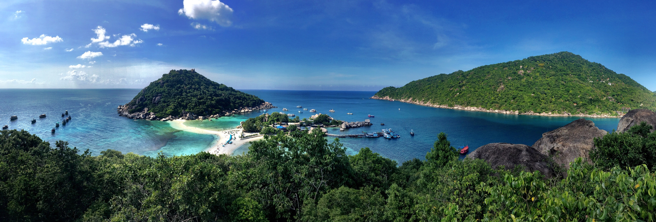 Overlooking beach with lush greenery, blue waters, and clear skies.