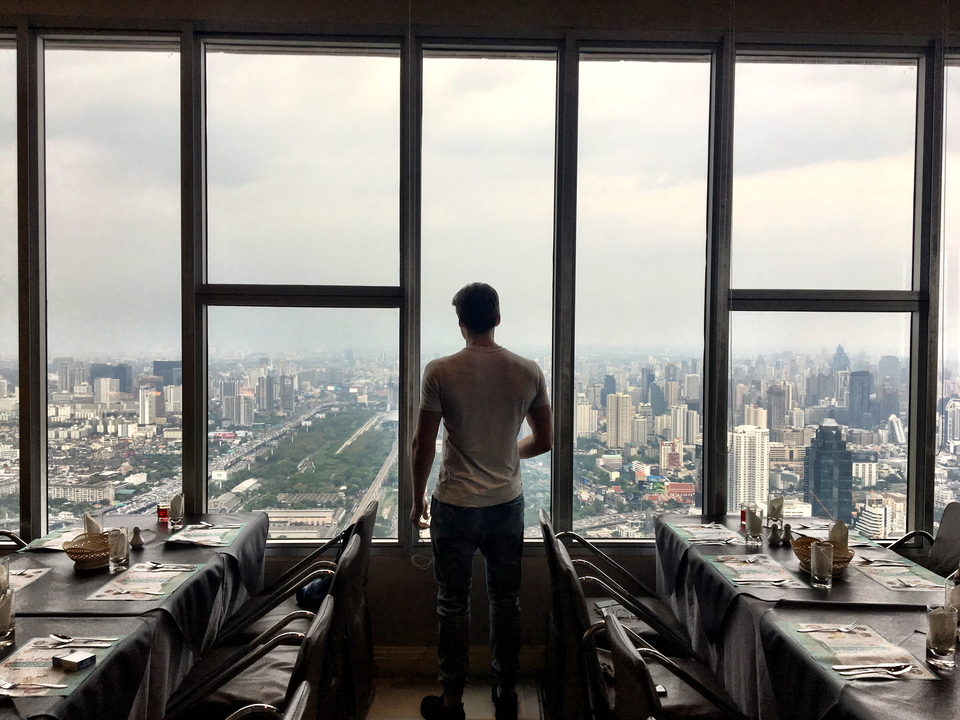 Man looking out from a high-rise with a cityscape in the background.