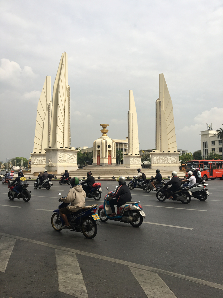 Traffic moves through a city with monument pillars in the middle.
