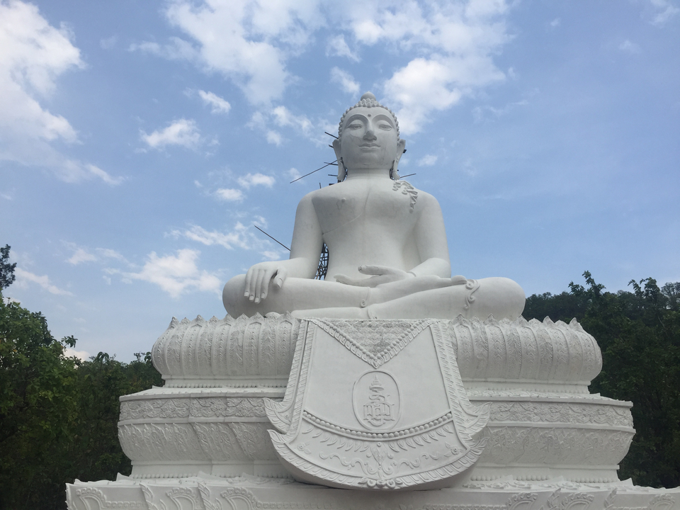 Large white Buddha statue against a bright blue sky.