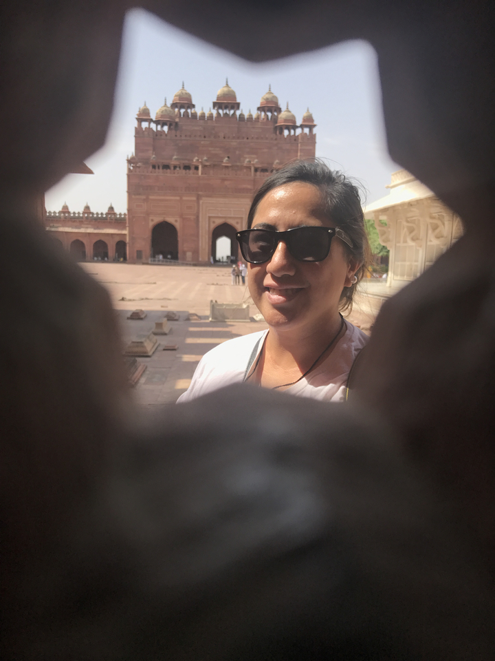 Personne souriant avec une architecture historique en arrière-plan.