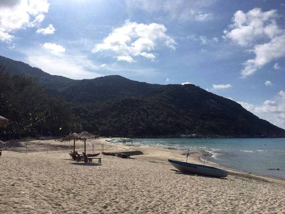 Empty beach with a small boat and mountains in the distance.