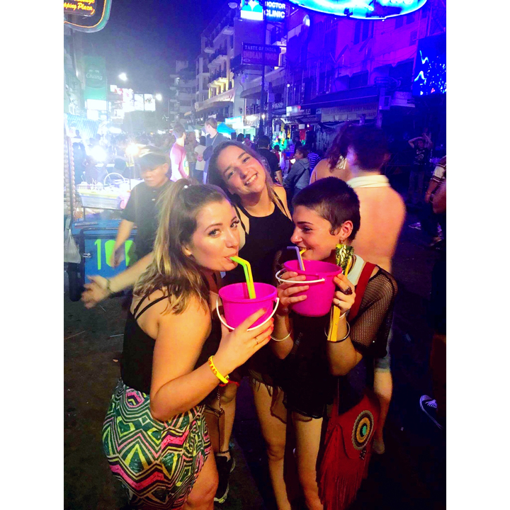 Jeunes femmes buvant des boissons dans des seaux lors d'un événement nocturne.