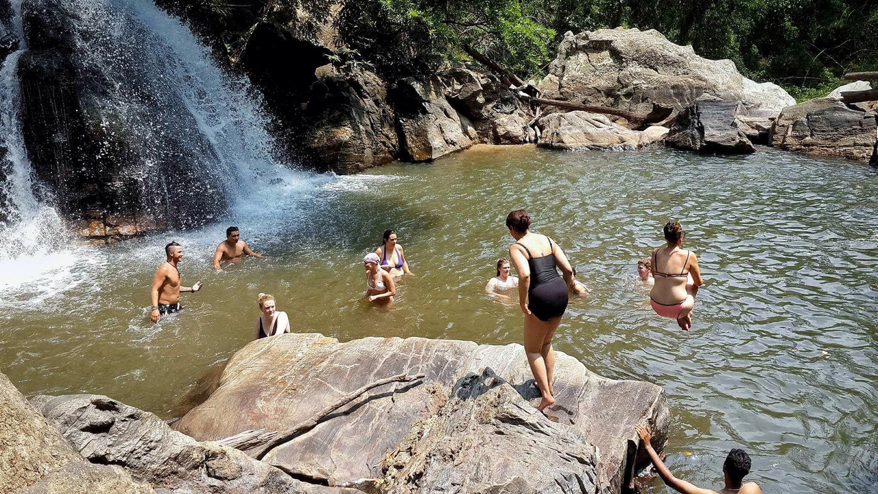 Group of people enjoying a waterfall in a natural setting.