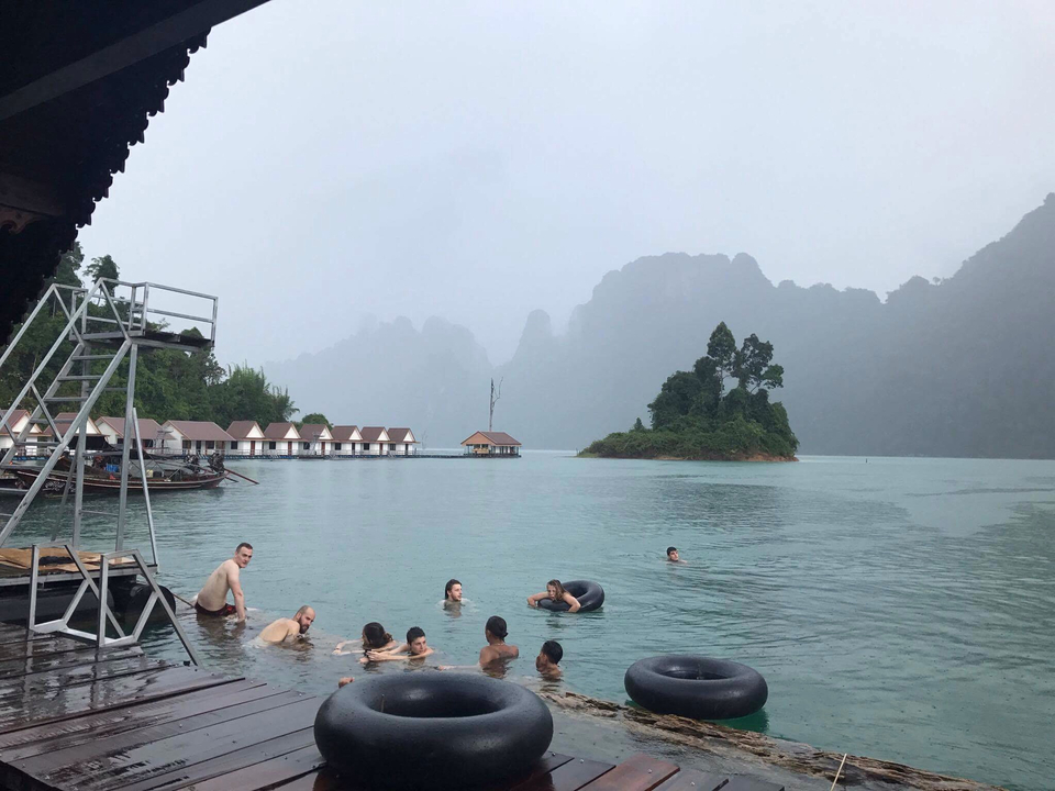 Group of people swimming in a scenic lake with limestone cliffs.