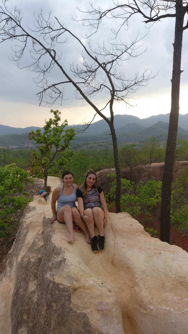 Two women sitting on a rocky path in a natural setting.