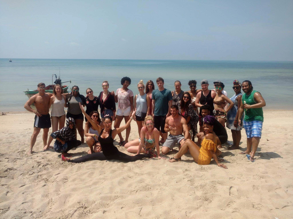 Beach group photo with smiling people in the sand.