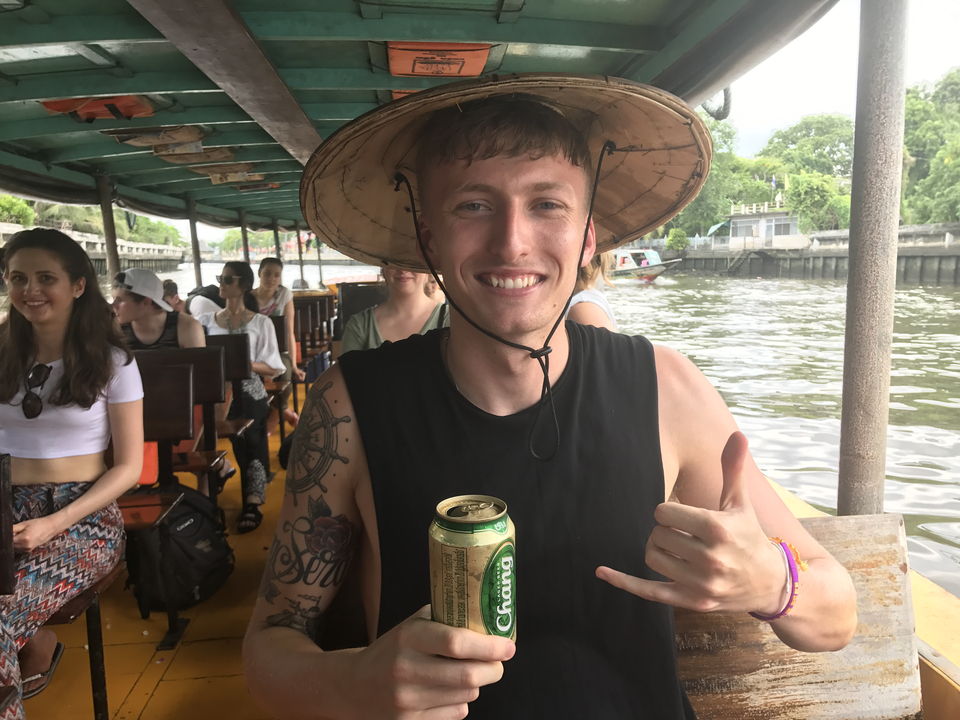 Man smiling with a drink on a tourist boat.