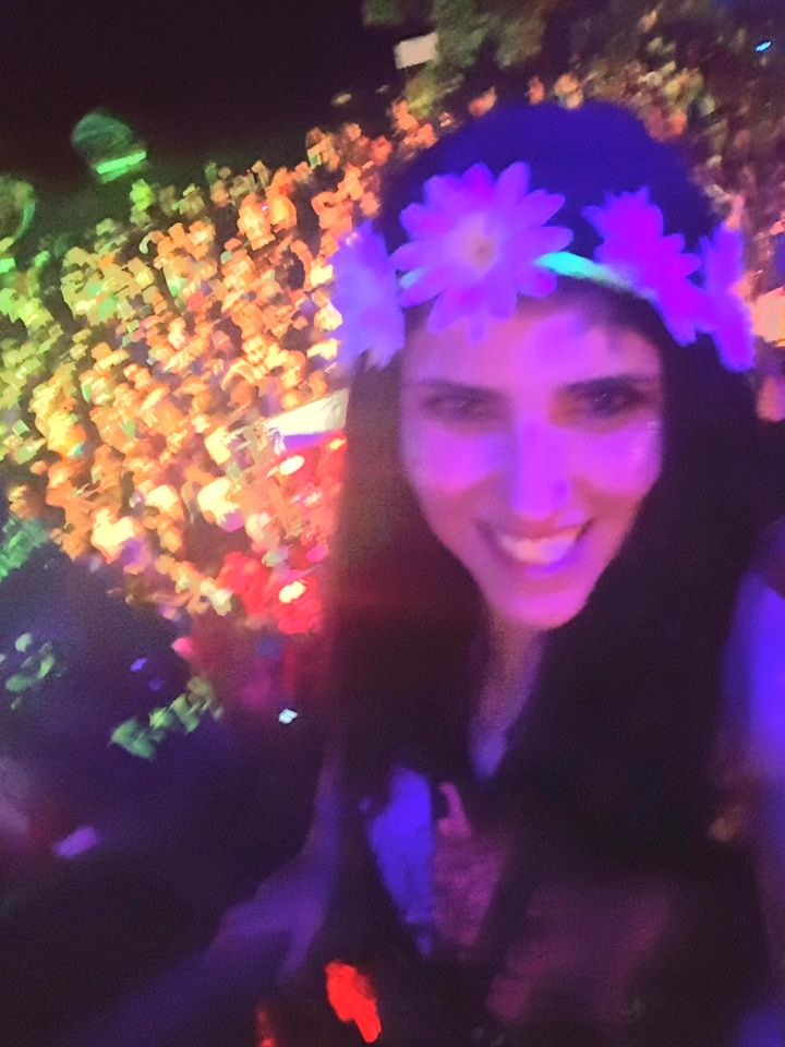 A blurry selfie of a person at a crowded, colorful event.