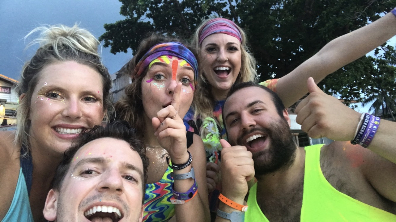 Group of friends with colorful face paint, showing excitement.