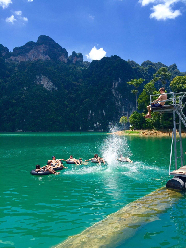 People floating in a lake while others create splashes in the water.