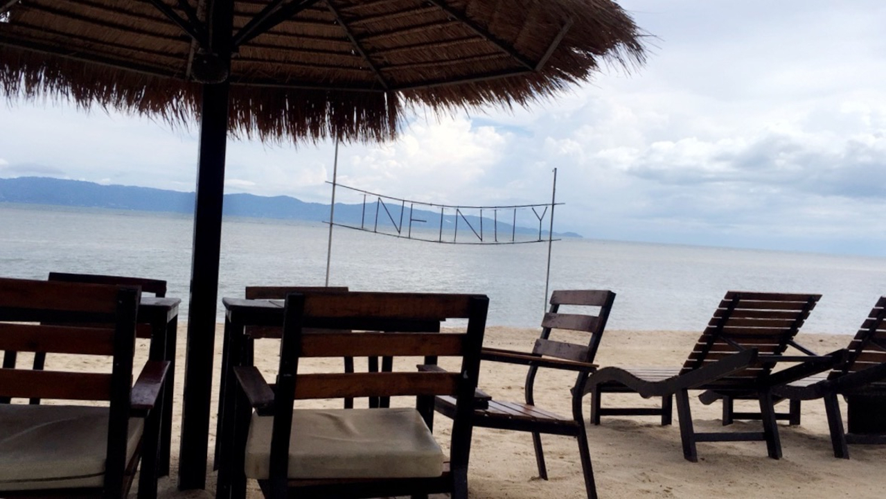 Beach scenery with loungers and a parasol looking out onto the sea.