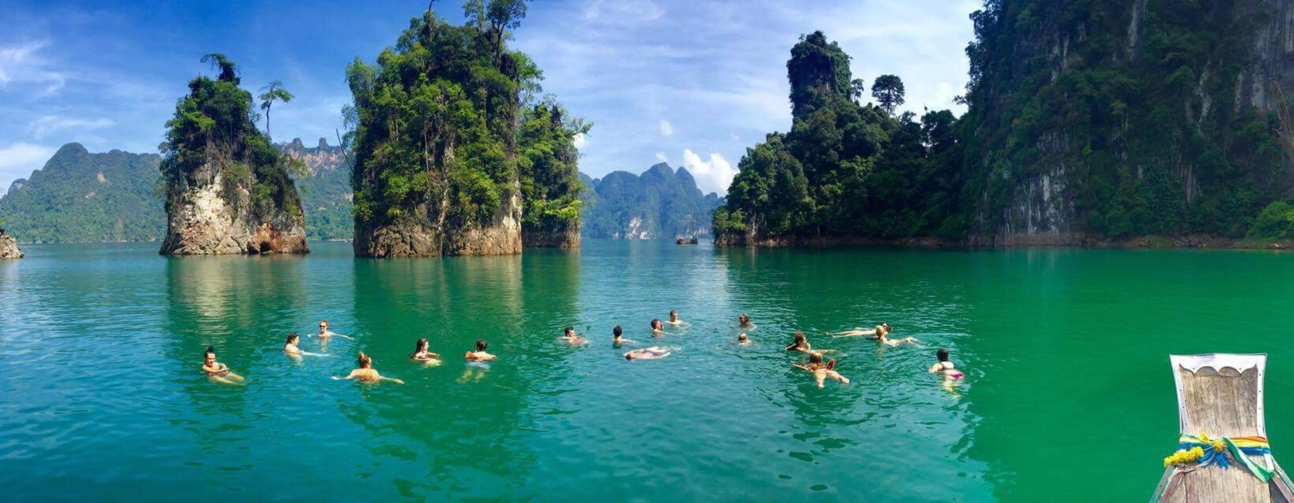Group of people swimming in turquoise waters surrounded by limestone islands.